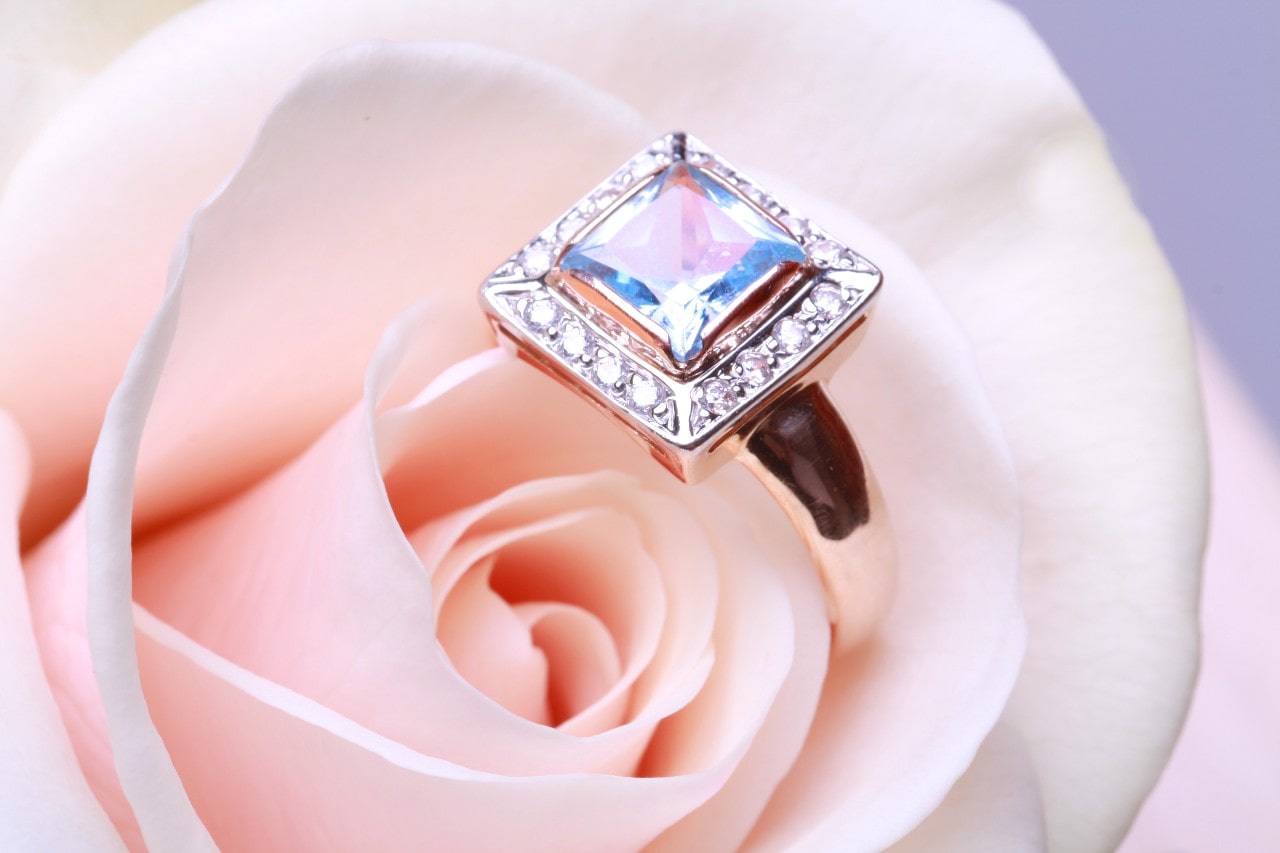 ENGAGEMENT RING WITH CUSHION CUT CENTER STONE SURROUNDED BY A DIAMOND HALO