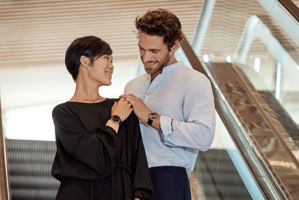 couple on an escalator wearing Rado watches