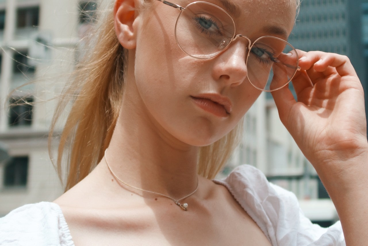 a woman in glasses wearing a very thin chained pearl pendant necklace